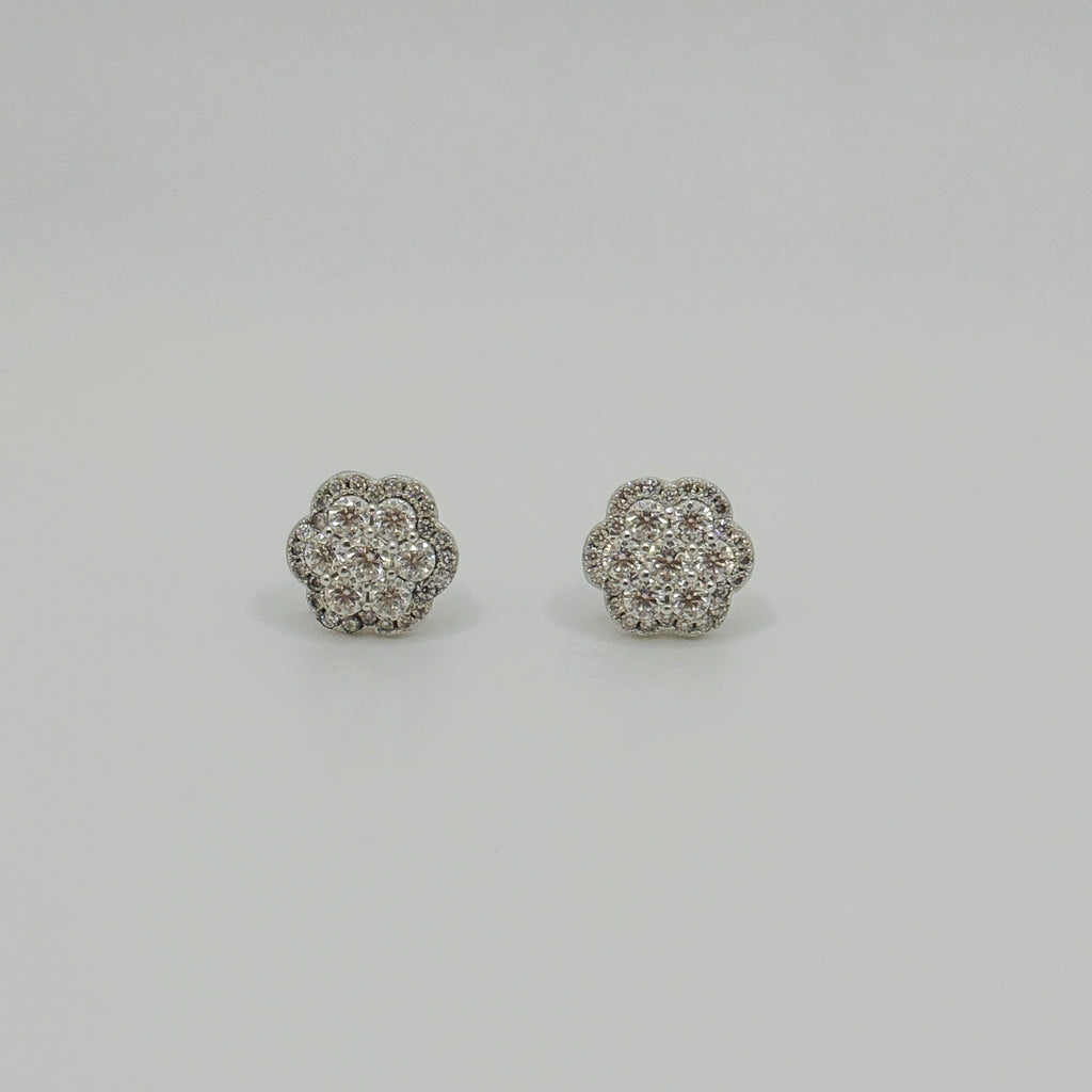 A pair of round flower-shaped stud earrings set with clear pavé gemstones in a silver-toned metal, displayed on a neutral light gray background.