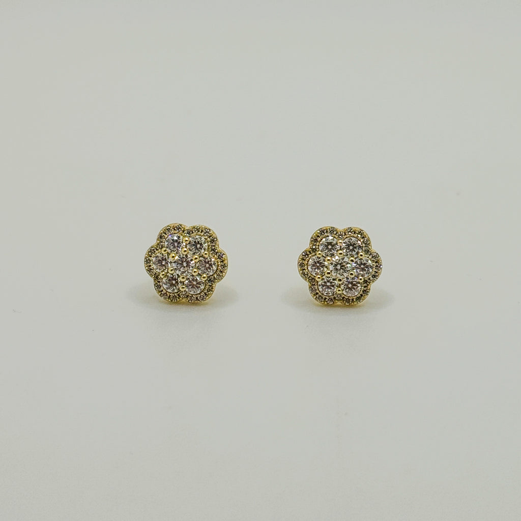 A pair of gold flower-shaped stud earrings with pavé-set clear stones, displayed on a clean, light gray background.