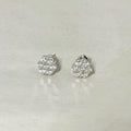 A pair of silver-toned stud earrings with round cluster pavé diamond settings, displayed on a light gray textured surface.