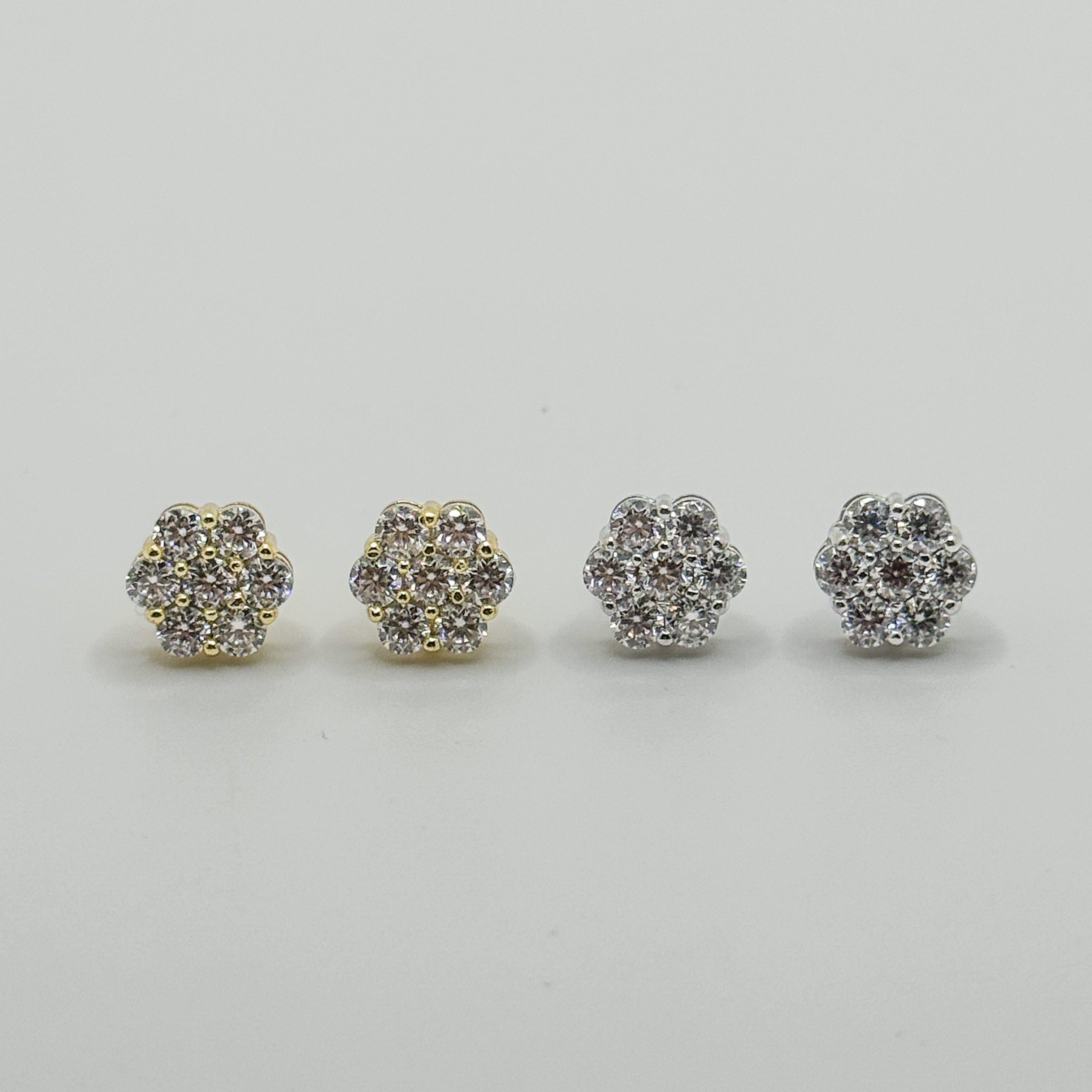 Four small pavé stud earrings arranged in a row on a light gray background. Two earrings have a yellow gold-tone setting with clear stones, and two have a silver-tone setting with clear stones.